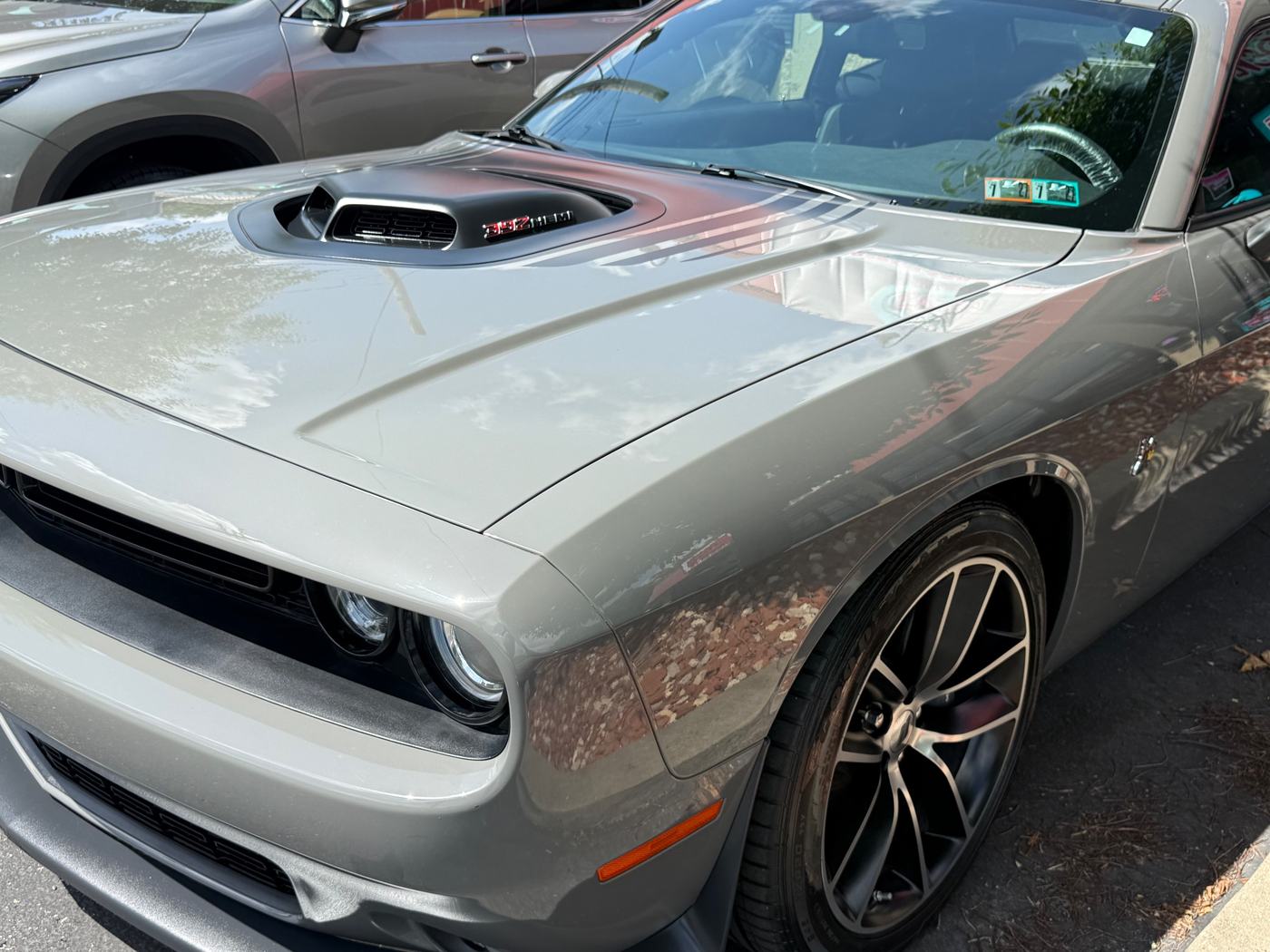 A grey Dodge Challenger covered in road film before its detail